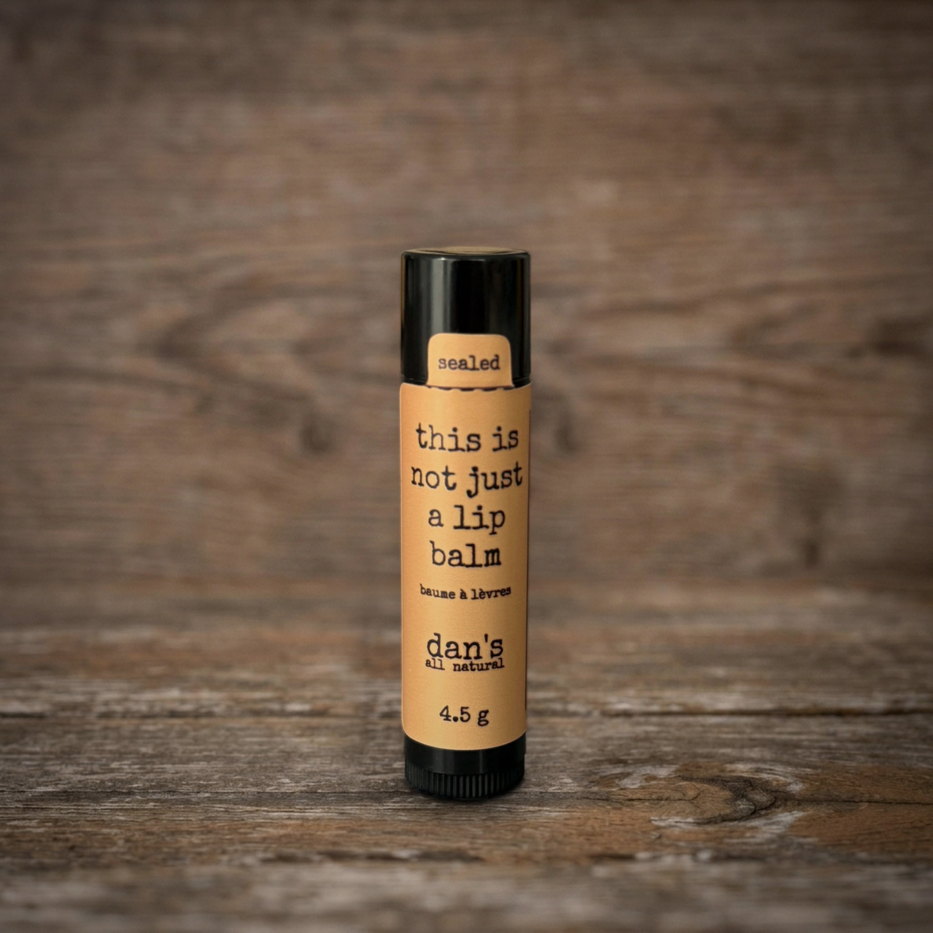 Dan's lip balm in a black tube with kraft 'this is not just a lip balm' label on weathered wood